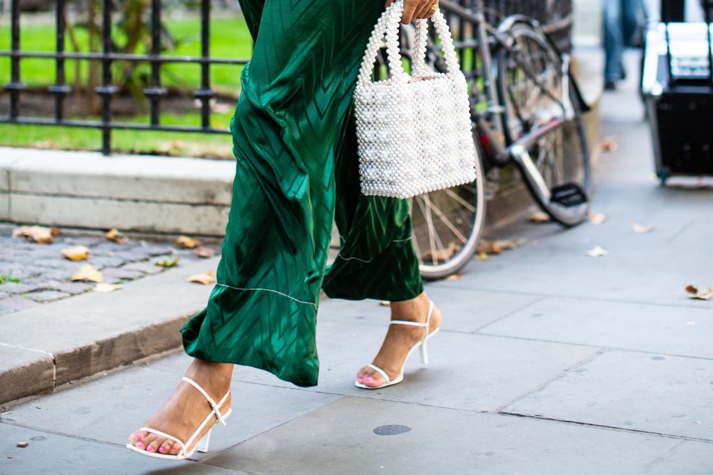 Fashionista mặc quần dài màu xanh lá cây đi giày sandals trắng